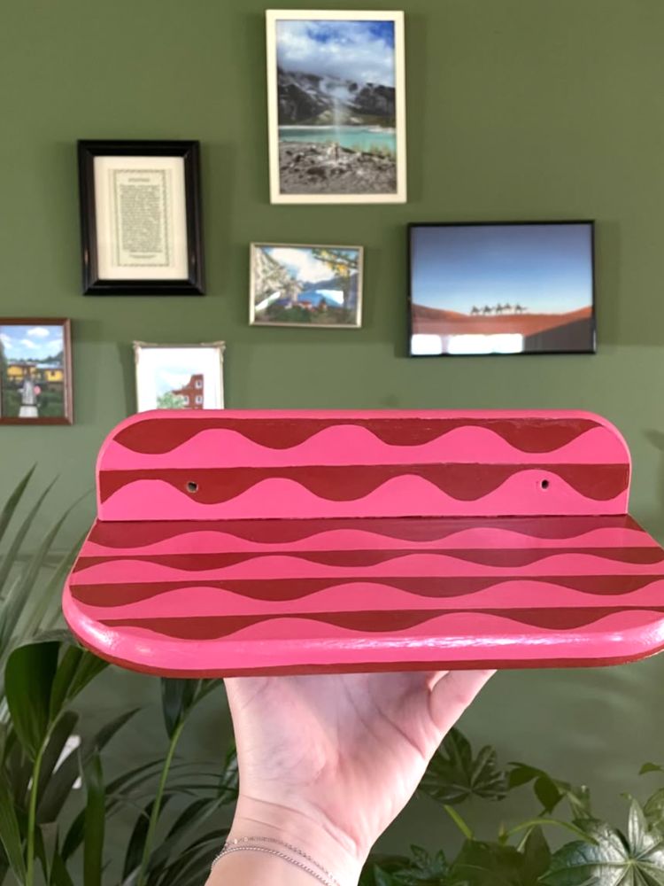 Zelf geschilderd wandplankje in roze en rood golfpatroon voor een groene fotowand