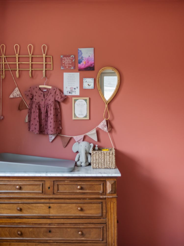 Kinderkamer met terracotta wand, opgeknapte vintage commode als aankleedtafel en wandhaakjes